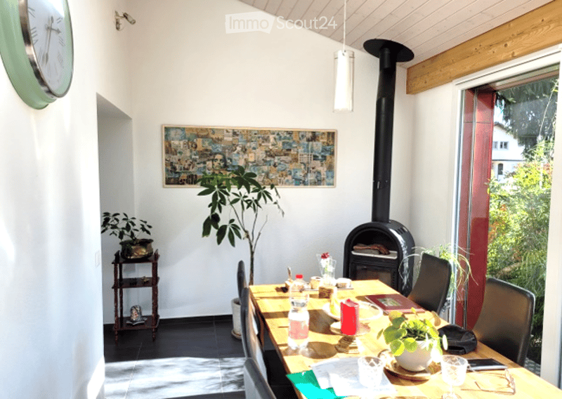 Bright dining area with a wooden dining table, chairs, fireplace, and decorative plants.