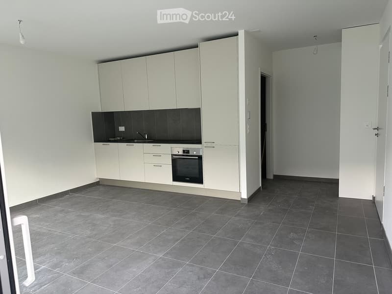 Modern kitchen with white cabinets, dark tiled backsplash, and grey tiled floor. Features a sink, oven, and built-in storage.