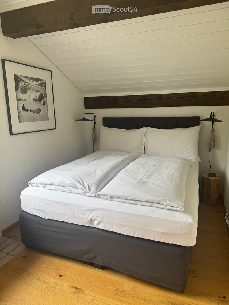 Cozy bedroom with a neatly made double bed, white bedding, wooden nightstands, and a framed picture on the wall.