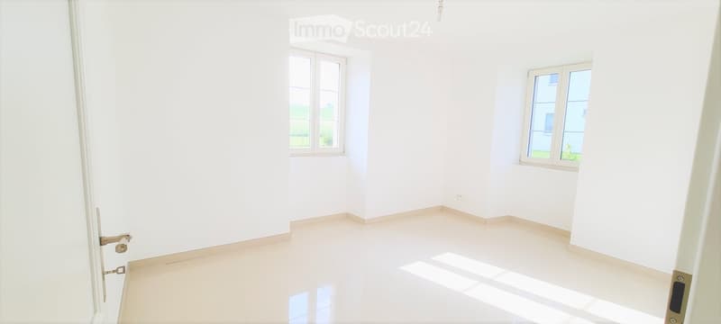 Empty room with white walls, tiled floor, and two windows allowing natural light.