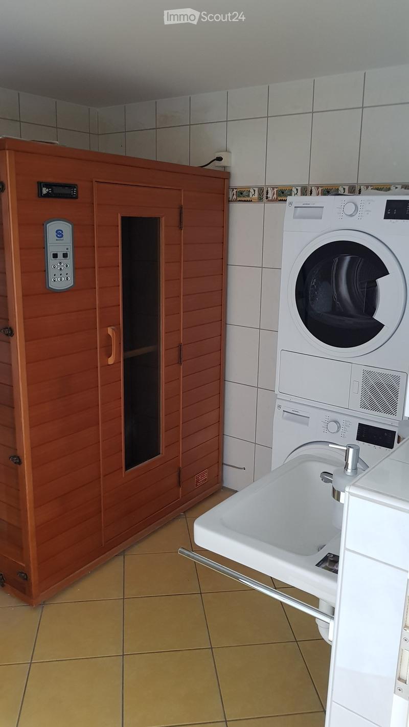 Bathroom with a white sink, a washing machine, and a wooden cabinet with a mirror.