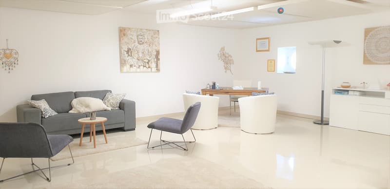 Modern living room with a grey sofa, wooden coffee table, white floor lamp, and decorative artwork on the walls.