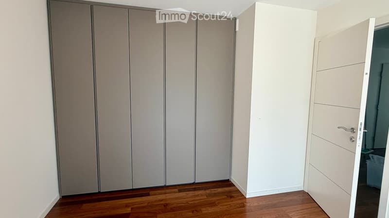 Empty room with wooden flooring, white walls, and built-in closet units.