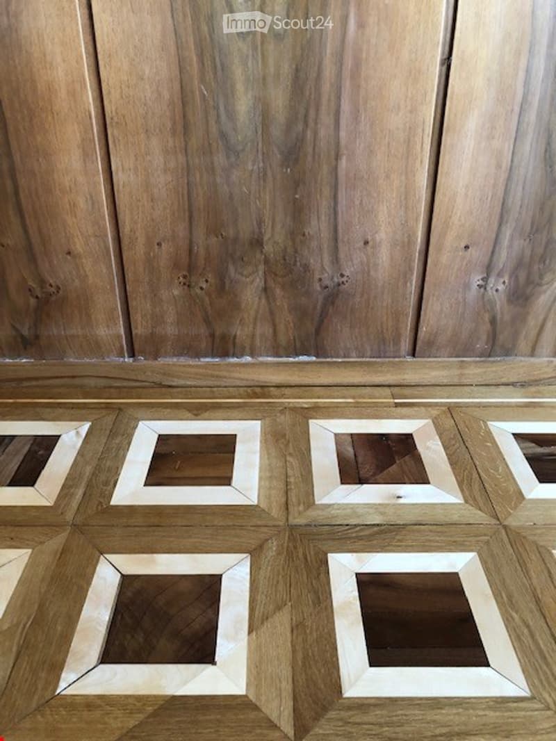 Empty room with wooden panel walls and a parquet floor featuring square inlays.