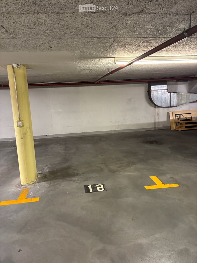 Underground parking space with concrete floor, yellow painted lines, and a numbered parking spot (18).
