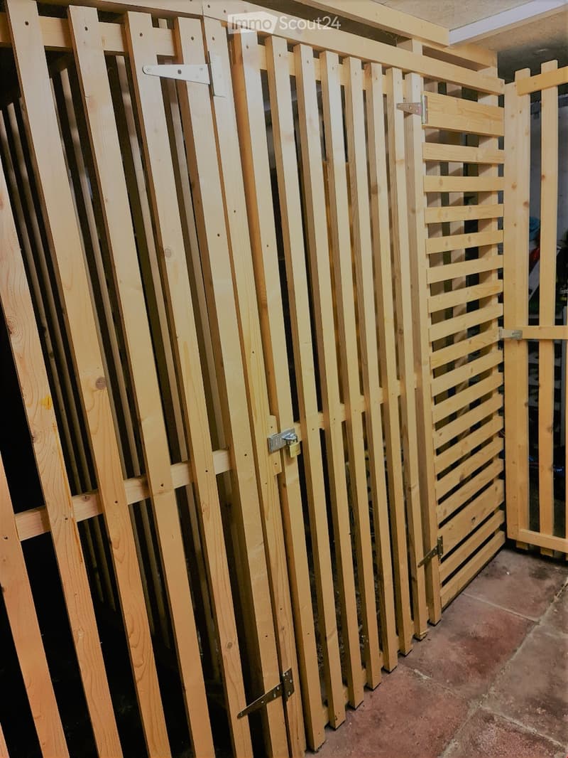 Empty room with wooden closet doors and frames stacked against the wall, showing unfinished interior with exposed wooden structures and metal hinges.