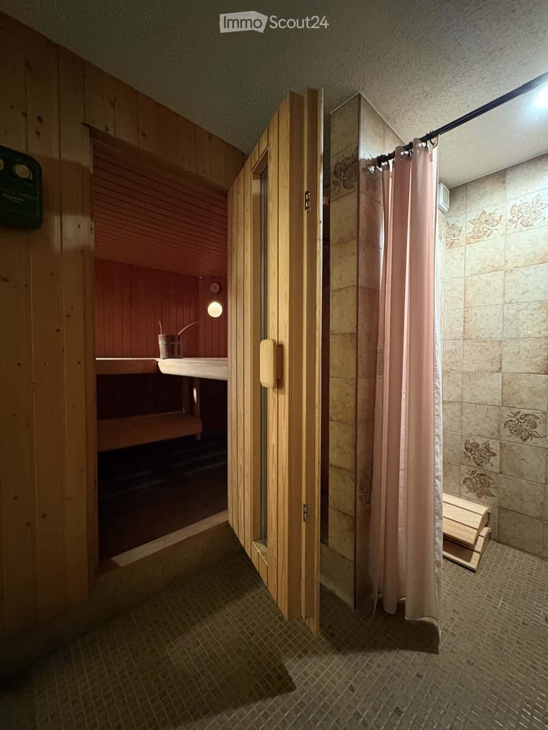Wooden sauna with a wooden bench, a shower curtain, and a small cup on a shelf inside.
