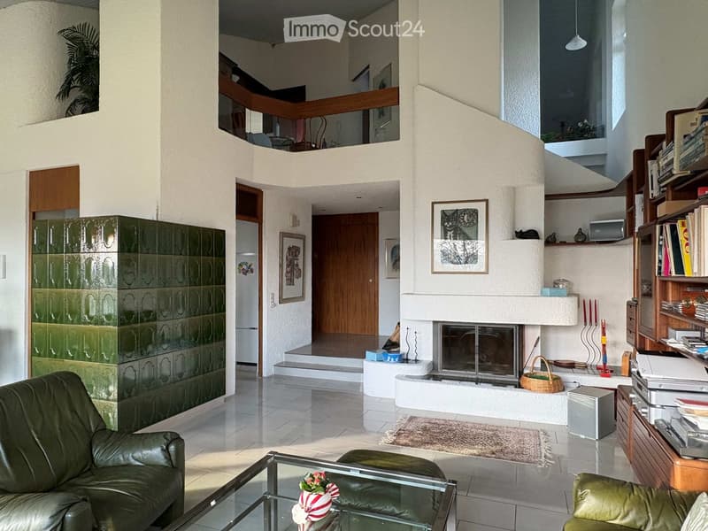 Modern living room with a fireplace, leather sofa, glass coffee table, bookshelf, and decorative items.