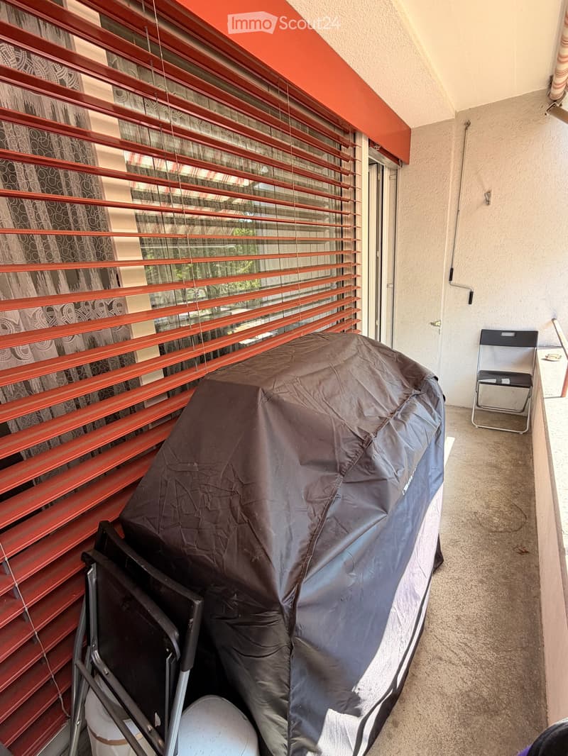 Balcony with covered hot tub, red blinds, and a single chair.