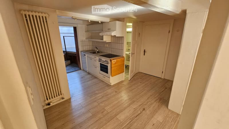 Modern kitchen with white cabinets, wooden floor, oven, dishwasher, and sink.