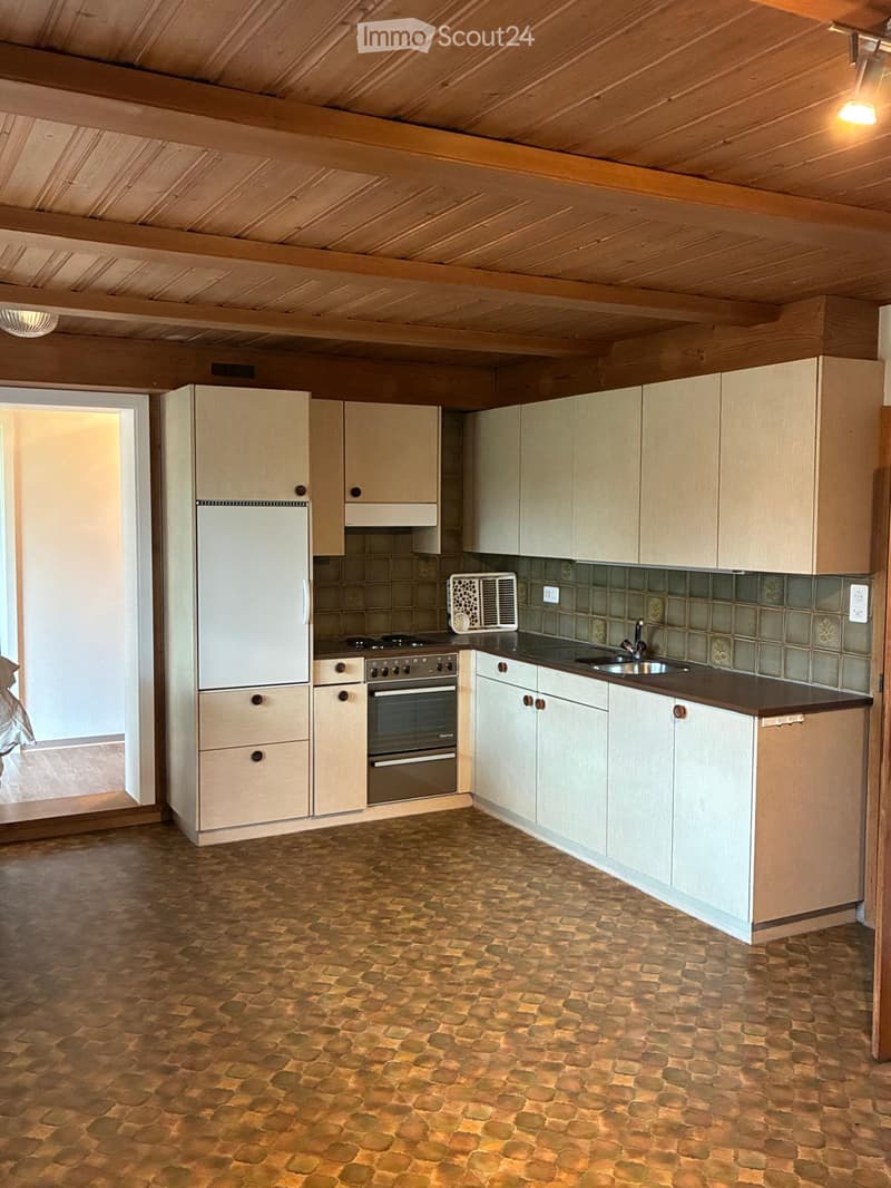 Bright kitchen with wooden cabinets, a stone-tiled floor, and modern appliances including a refrigerator, oven, and sink.