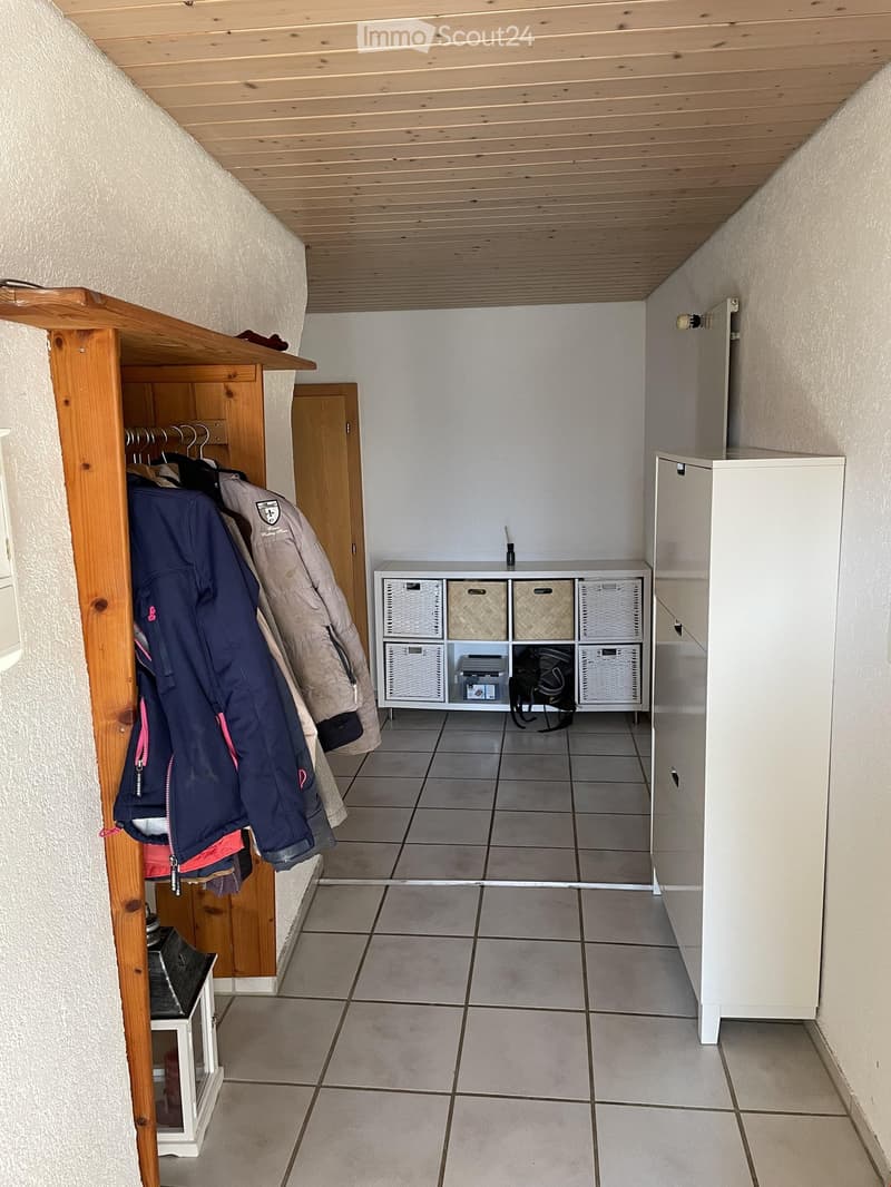 Hallway with tiled floor, wooden coat rack, storage unit with baskets, and white cabinet.