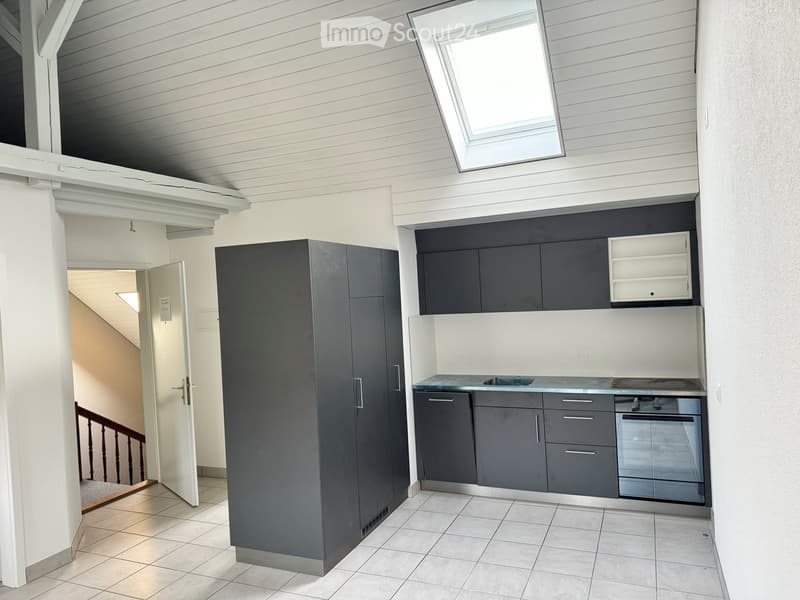 Modern kitchen with grey cabinets, stainless steel appliances, and a white countertop. Features a built-in sink, stove, and oven, with a small open shelving unit above.