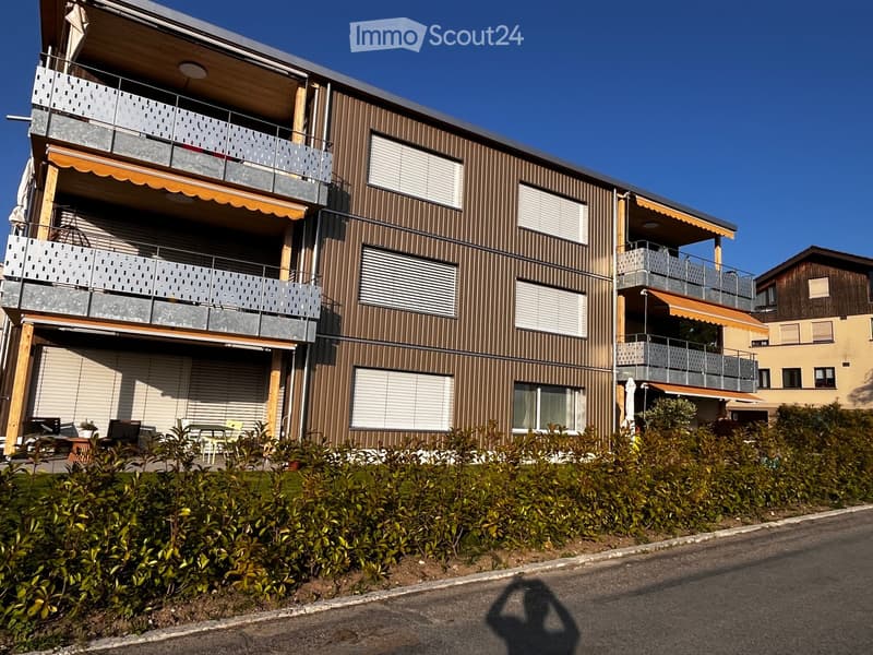 multi-story building, brown exterior, multiple balconies, glass doors, outdoor seating area