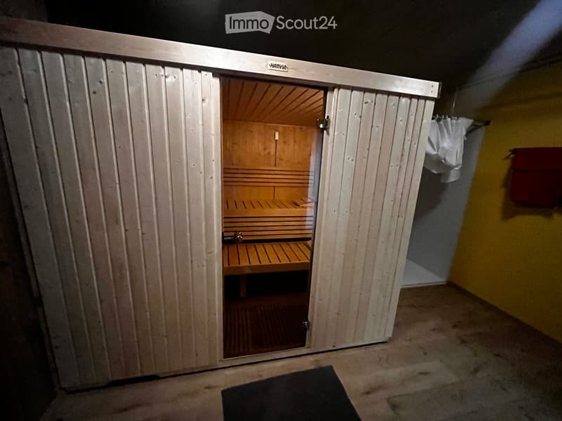 Wooden sauna with white lining, open door, wooden bench, yellow wall, black rug, white curtain