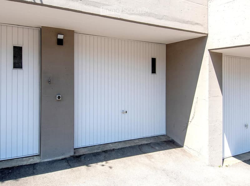 A modern, minimalist garage with white panel doors and a clean, contemporary design.