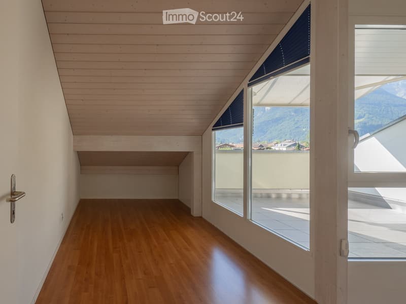 Empty room with wooden flooring, white walls, and large windows offering a scenic mountain view.