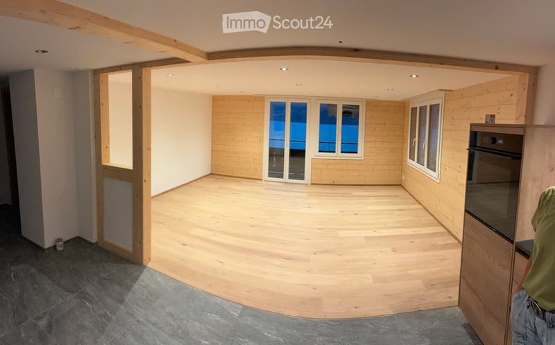 Empty room with wooden flooring, white walls, large windows, and exposed wooden beams on the ceiling. No furniture or equipment present.