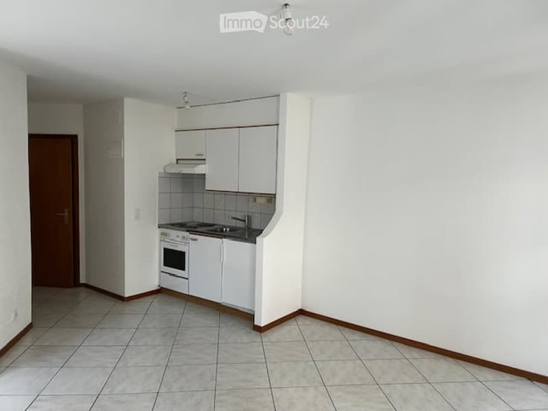 Modern kitchen with white cabinets, tiled floor, and stainless steel appliances including an oven and sink.