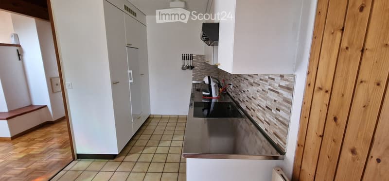 Modern kitchen with white cabinets, stainless steel appliances, and a tiled backsplash. The space features a wooden floor and a built-in stove with a sink nearby.