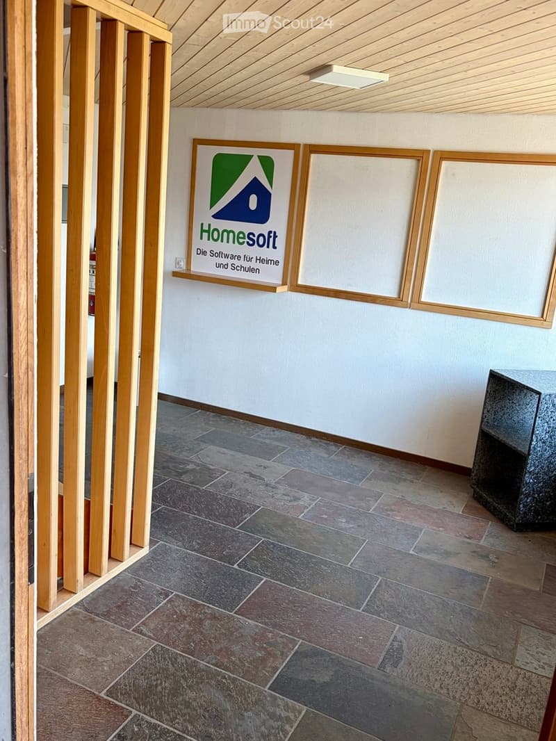 Empty hallway with tiled floor, light wooden ceiling, and a sign reading "Homesoft" on the wall.