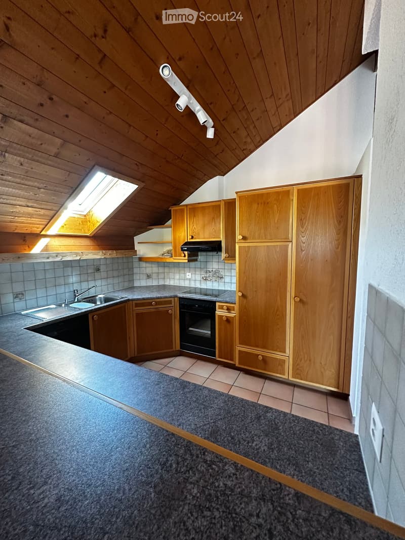 Attic kitchen with wooden cabinets, stainless steel sink, oven, and skylight window providing natural light.