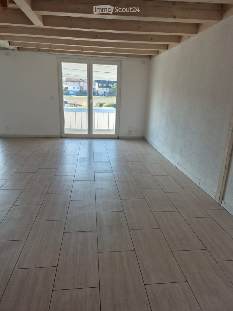 Empty room with tiled flooring, white walls, and a large sliding glass door leading to a balcony.