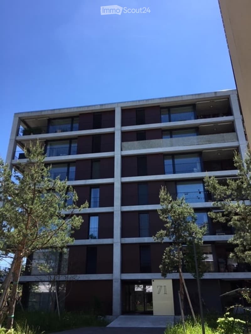 Modern multi-story apartment building with balconies, large windows, and a contemporary design.