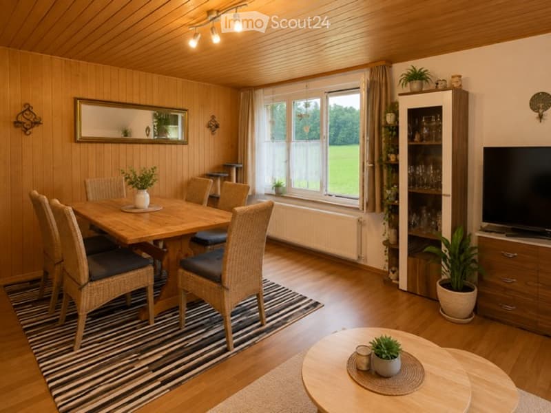 Cozy dining and living area with wooden walls and floors, a dining table with chairs, a TV cabinet, and decorative plants.