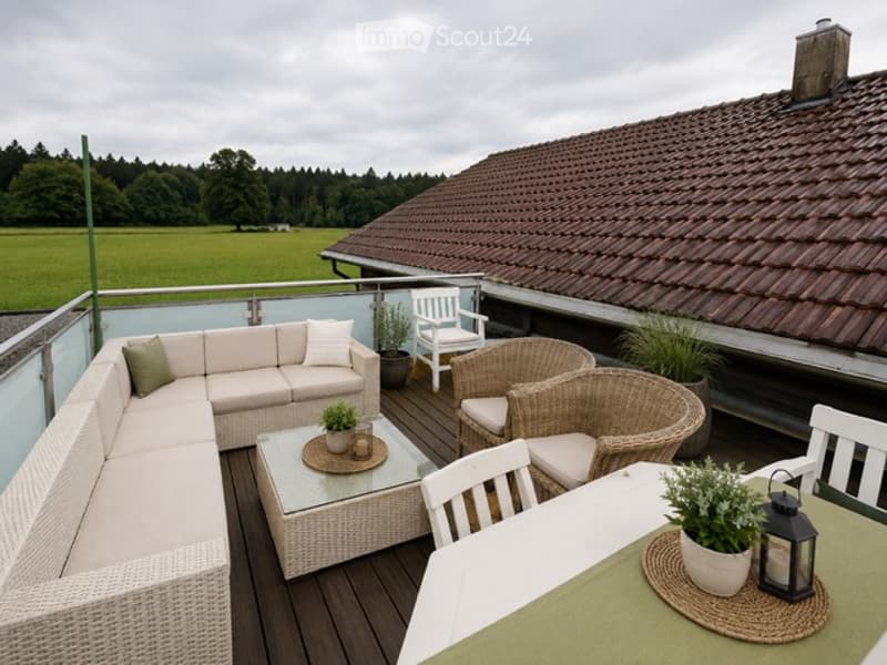 Outdoor terrace with wooden decking, white sectional sofa, wicker chairs, glass coffee table, dining table, and potted plants.