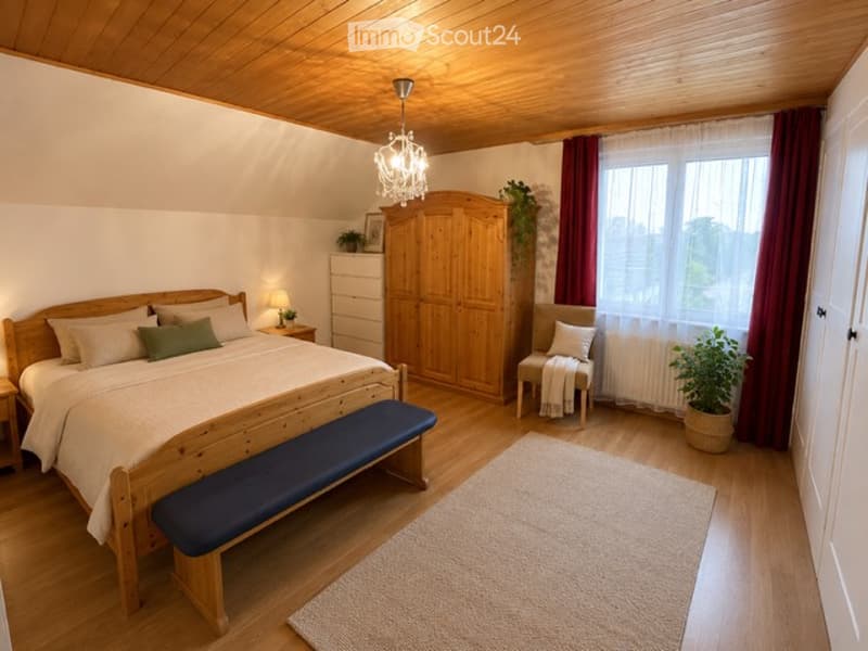 Cozy attic bedroom with wooden floors and ceiling, featuring a large bed with green and white bedding, a wooden bench at the foot, a wardrobe, a small table with a lamp, a chair with a throw, and potted plants near the window.