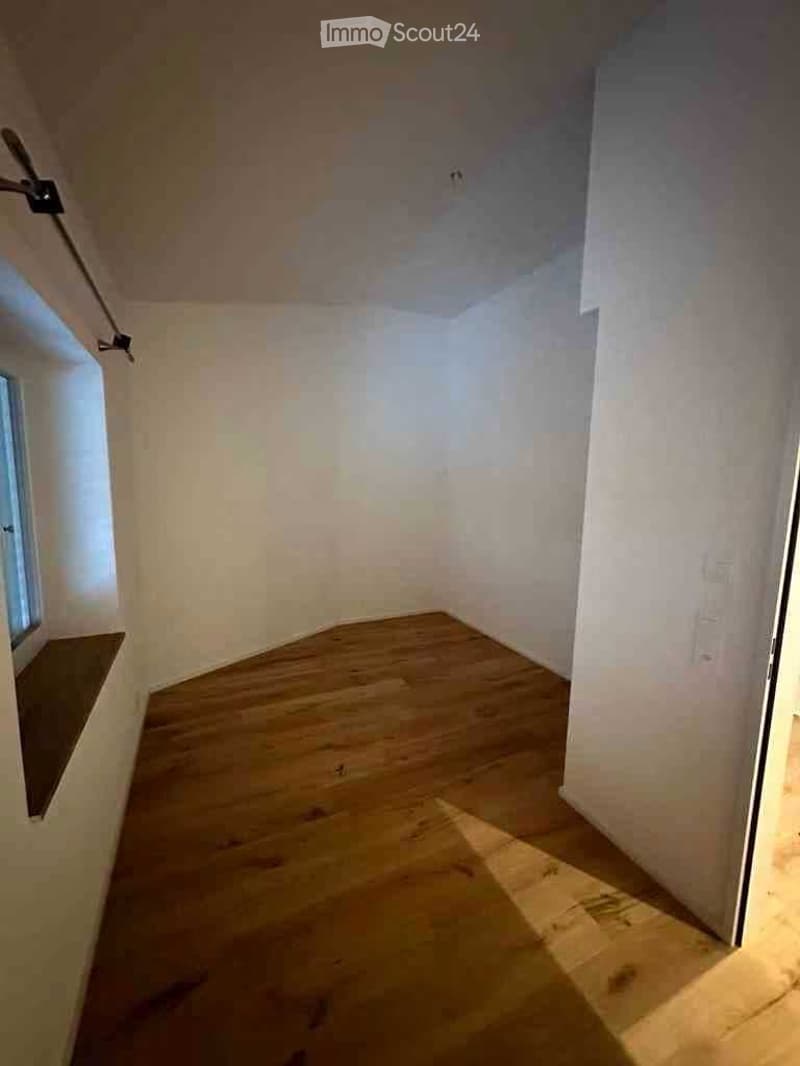 Empty room with wooden flooring, white walls, and a small window letting in natural light. No furniture or equipment is present.