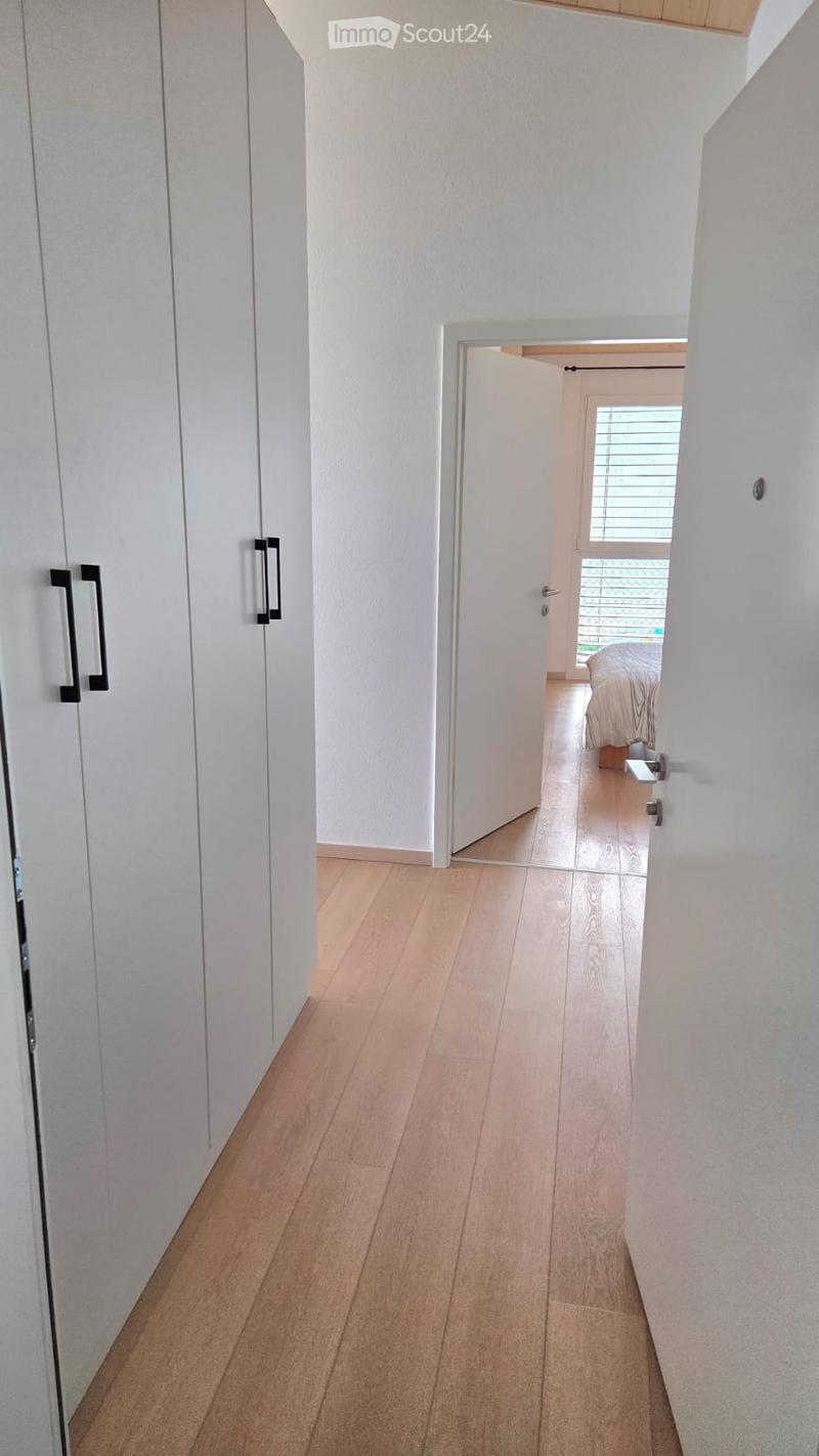 wooden floor, white walls, large wardrobe, open door, bedroom with bed and window