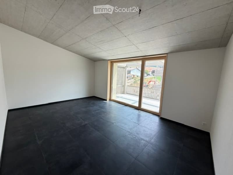 Empty room with dark tiled floor, white walls, and a large sliding glass door leading to a balcony.