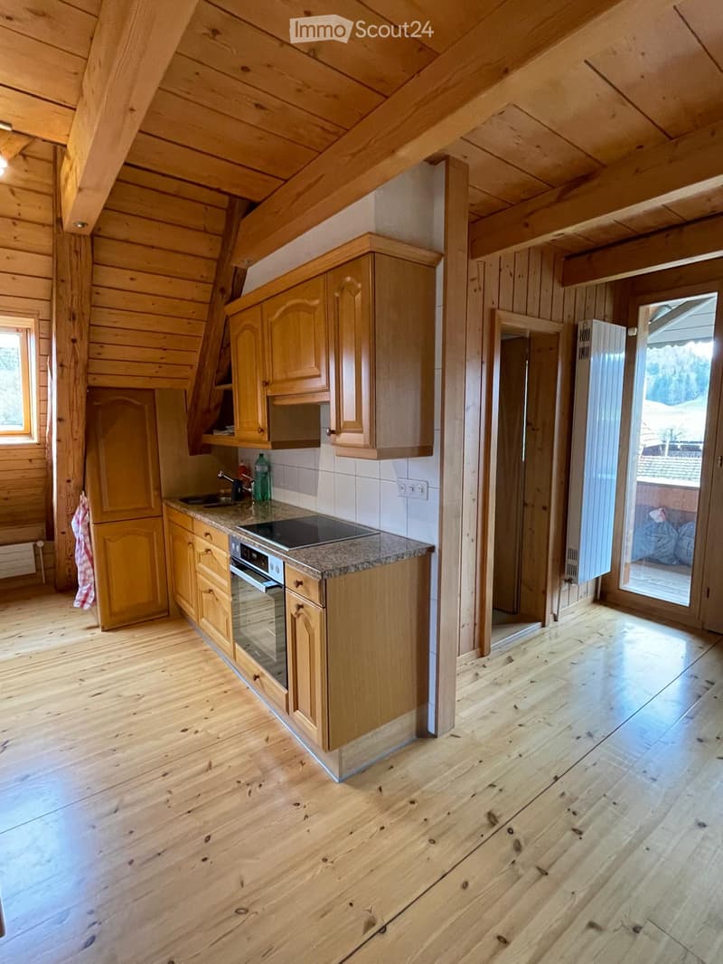 Bright kitchen with wooden cabinets, granite countertop, and a modern oven. The space features wooden floors and large windows, with a door leading to an outdoor area.