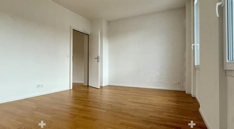 Empty room with wooden flooring, white walls, and a doorway leading to another space. No furniture or equipment is present.
