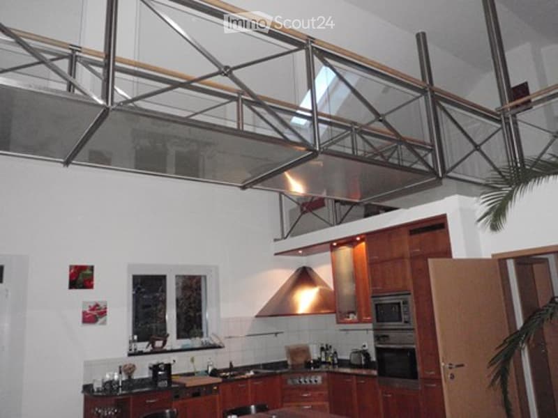 Modern kitchen with wooden cabinets, stainless steel appliances, a central island, and a large window. The space features a sleek design with built-in storage and a hanging light fixture above the island.