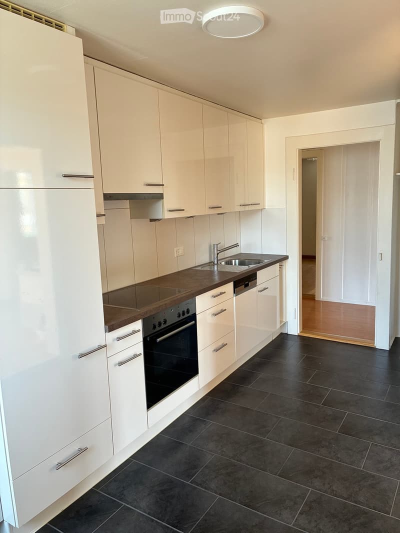Modern kitchen with white cabinets, dark countertops, and black tiled flooring. Features include a sink, faucet, oven, and dishwasher.