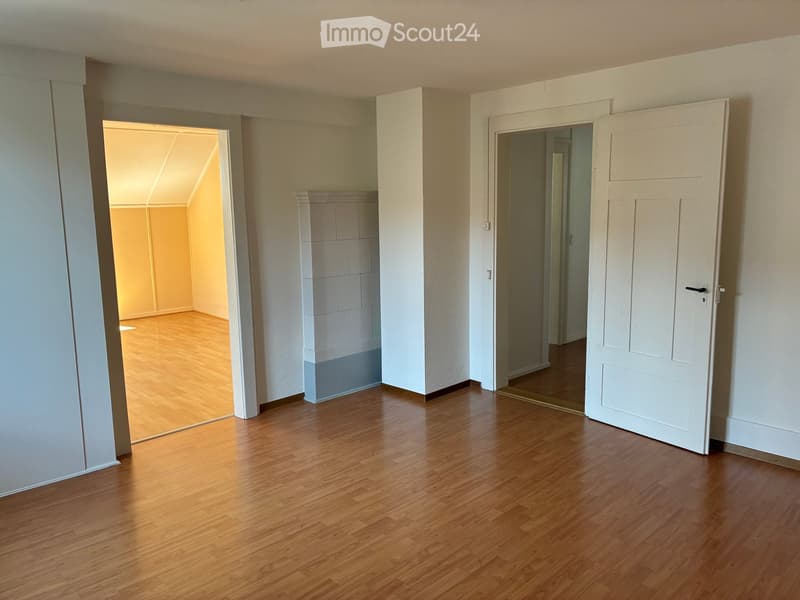 Empty room with wooden flooring, white walls, and two open doors leading to other rooms.