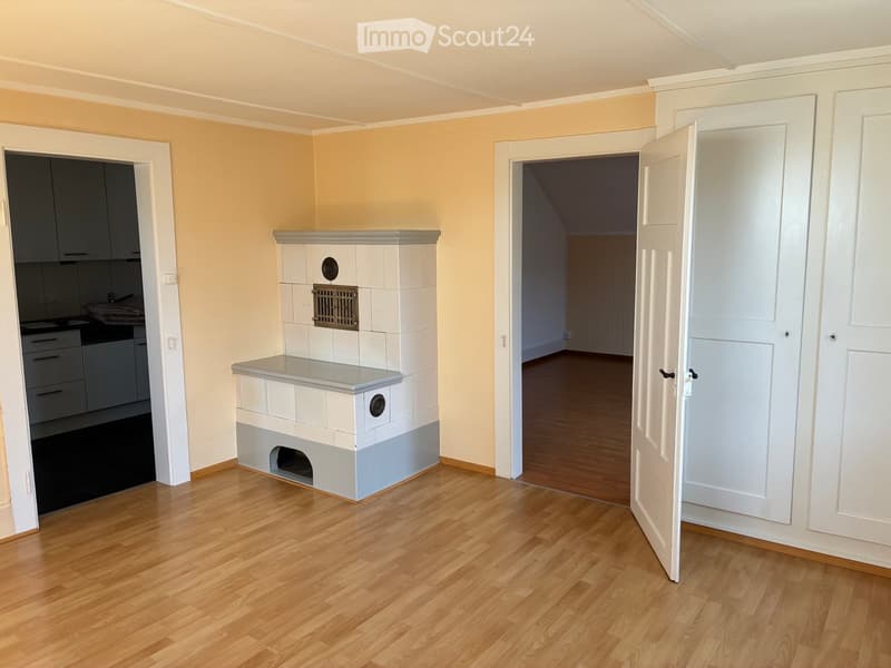 Empty room with wooden flooring, light-colored walls, and a fireplace with a tiled surround. There are two open doors leading to other rooms.