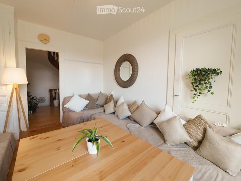 Modern living room with a grey sofa, wooden coffee table, floor lamp, and decorative mirror on the wall.