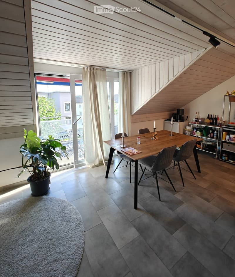 Modern dining area with wooden table, chairs, potted plant, and open sliding doors leading to a balcony.