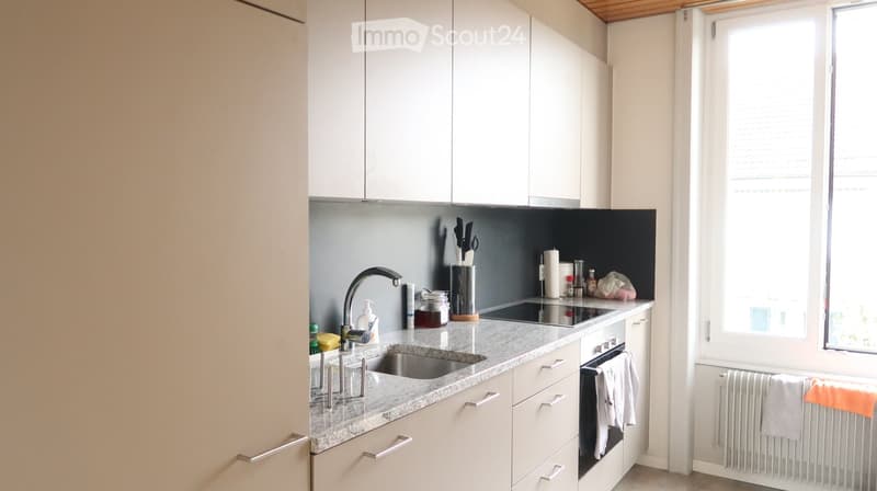 Modern kitchen with white cabinets, granite countertop, stainless steel sink and faucet, built-in oven, and various kitchen items on the counter.