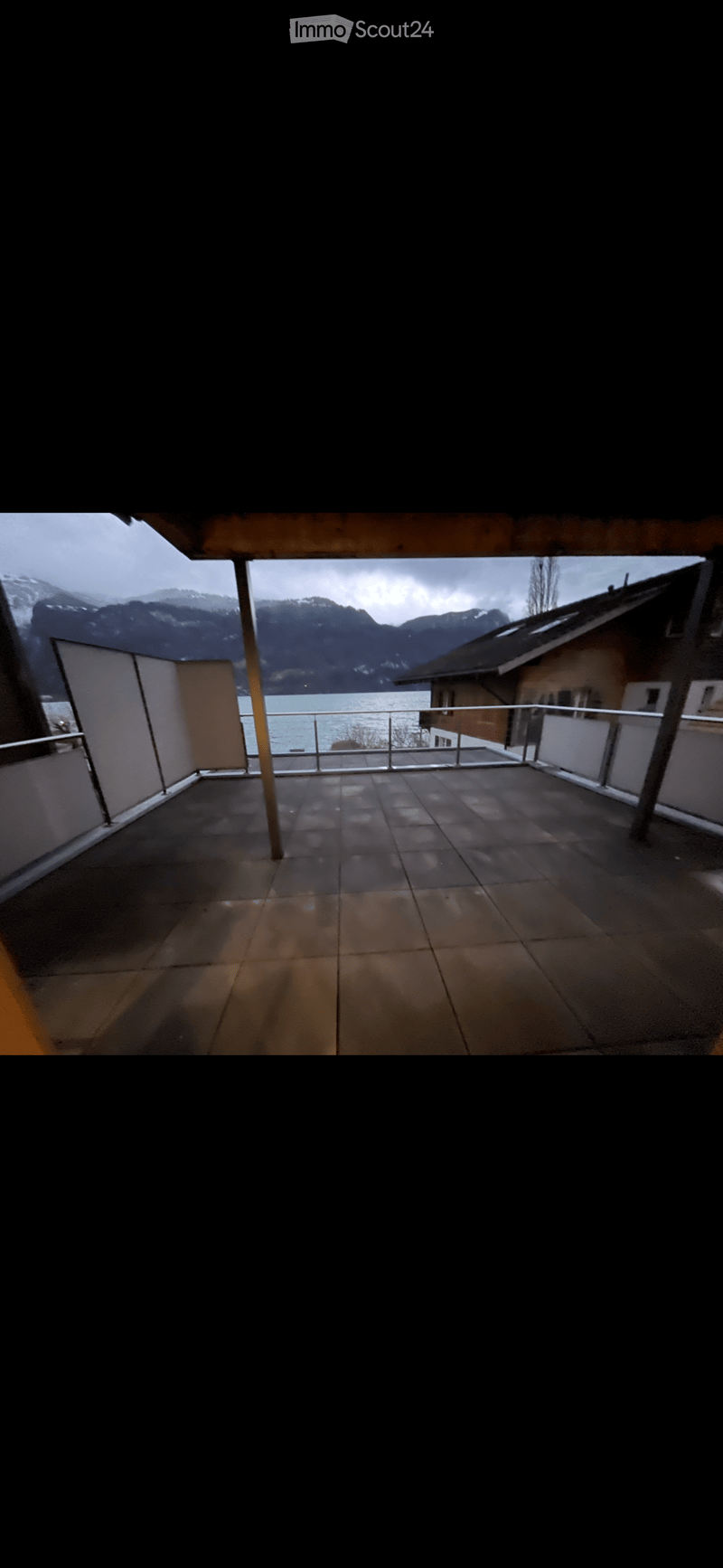 Empty balcony with tiled floor, metal railing, and scenic mountain and lake view.