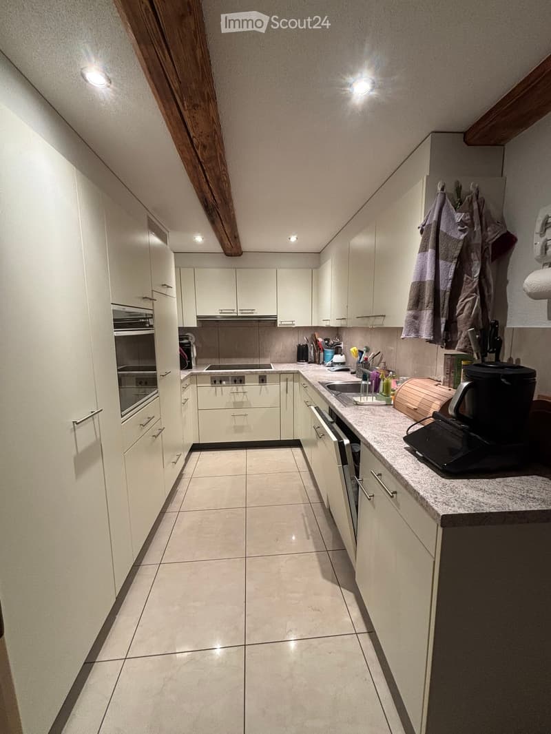 Modern kitchen with white cabinets, granite countertop, built-in oven, dishwasher, and various appliances.