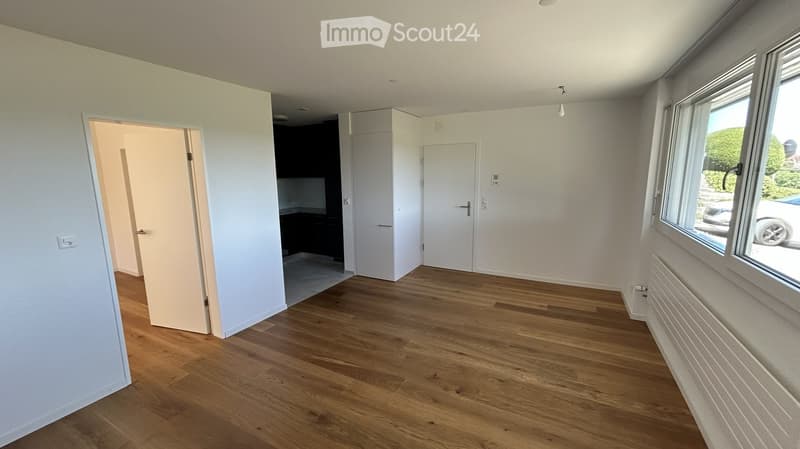 Empty room with wooden flooring, white walls, and large windows. No furniture or equipment is present.