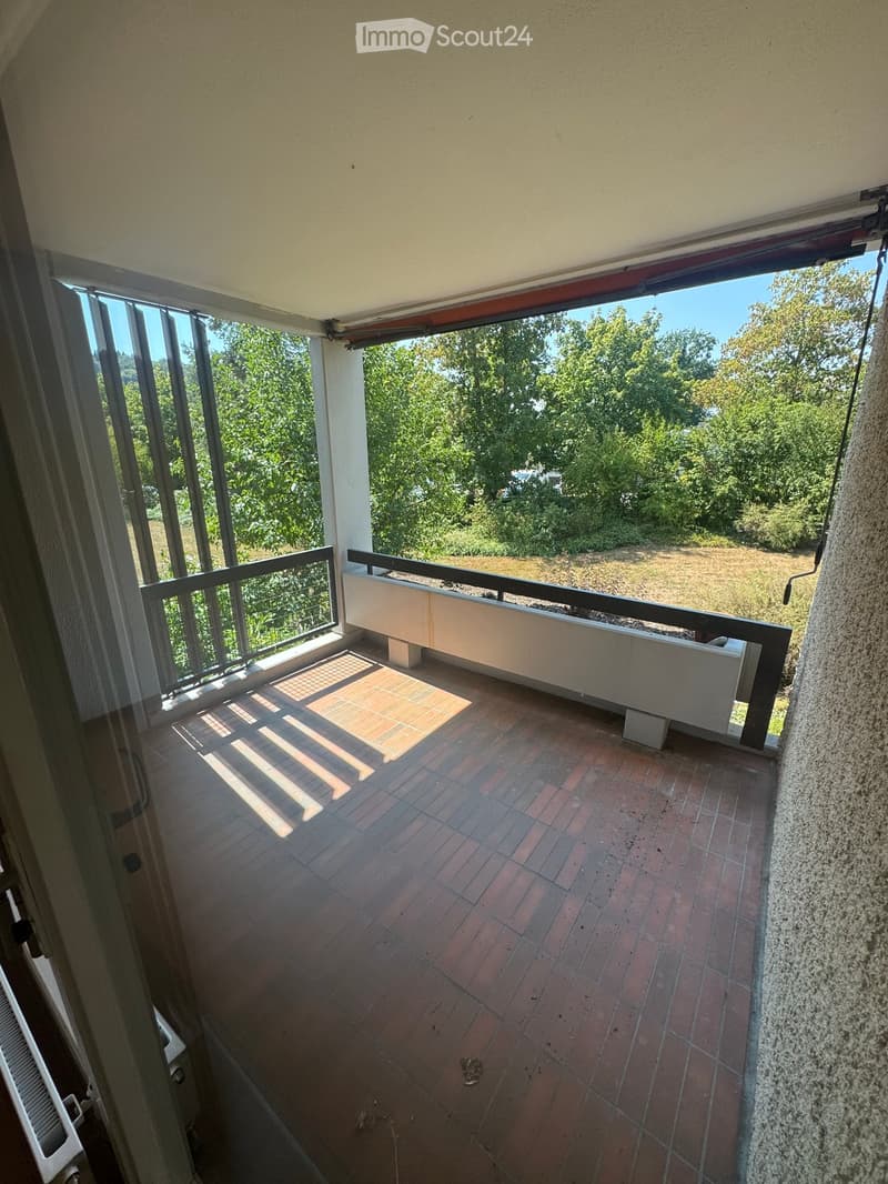 Balcony with brick tiles, metal railing, and a view of greenery and open field.
