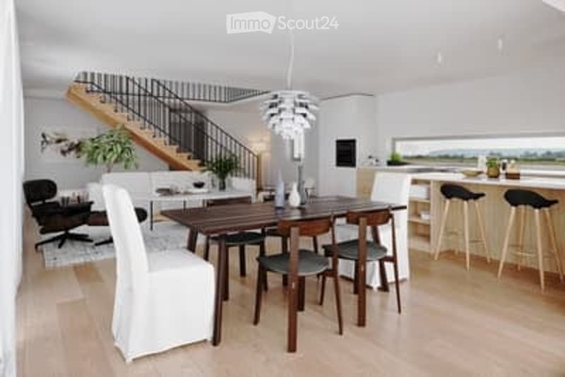 Bright, modern dining area with a wooden dining table, white chairs, and a sleek black sofa. A small kitchen area with bar stools is visible in the background, along with a staircase leading to an upper level.