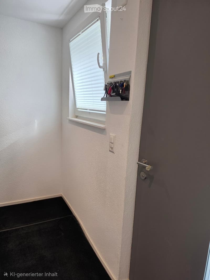 A narrow hallway with white walls, black tiled floor, a window with blinds, a door, and a small shelf holding keys and a light switch.