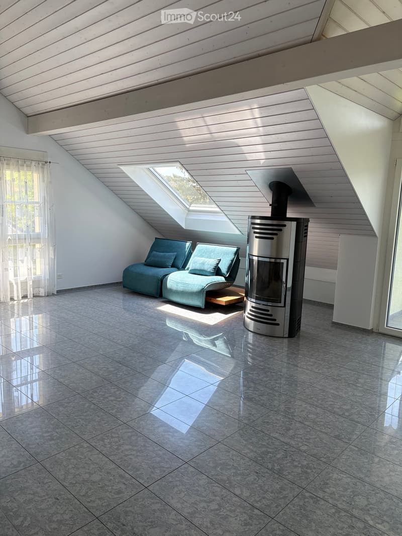 Modern living room with a sleek, contemporary fireplace, a comfortable sofa, and a small wooden table, featuring large windows and a skylight.